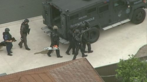 One officer appeared to be carrying a chainsaw to tackle the house's door. (9NEWS)