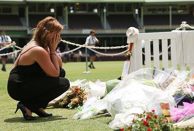 A woman reacts after putting flowers down at the Randwick End.