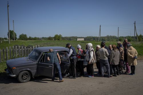 Villagers queue to buy cigarettes and bread from a peddler in the village of Staryi Saltiv, east Kharkiv, Ukraine, Friday, May 20, 2022. The village formerly occupied by Russian forces is back under Ukrainian control, albeit very close to the front line and under constant shelling. (AP Photo/Bernat Armangue)