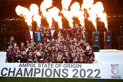 The Maroon playing group celebrate raising the Origin shield after capturing the series 2-1.