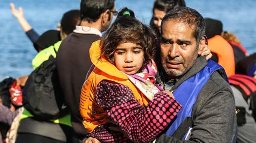 A man holds a girl after their arrival on a dinghy from the Turkish coast to the Greek island of Lesbos. (AAP)