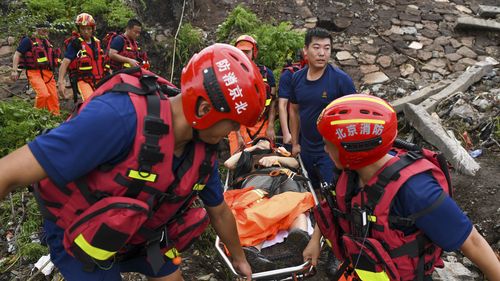 In this photo released by Xinhua News Agency, rescuers carry an injured person from a flood-hit village in Mentougou district on the outskirts of Beijing on Tuesday, Aug. 1, 2023. China's capital has recorded its heaviest rainfall in at least 140 years over the past few days after being deluged with heavy rains from the remnants of Typhoon Doksuri. (Ju Huanzong/Xinhua via AP)