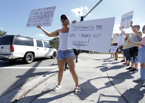 Juliana Cruz stands on a street corner holding up an anti-gun sign in Parkland. (AAP)