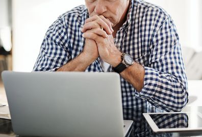 Shot of a mature man looking anxious while working on a laptop at home