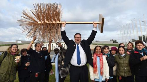  Independent Senator Glenn Lazarus lifts a golden toilet brush with striking Parliament House cleaners outside Parliament House in Canberra. (AAP)