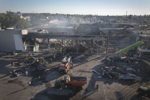 Ukrainian State Emergency Service firefighters work to take away debris at a shopping center burned after a rocket attack in Kremenchuk, Ukraine on Tuesday.