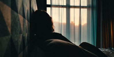 woman sitting on bed in front of window