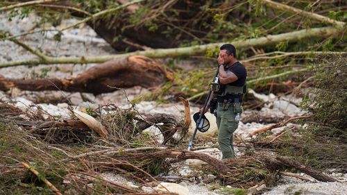 A Sheriff's deputy pauses while combing through the banks of the Guadalupe River near Camp Mystic on July 5 in Hunt, Texas.