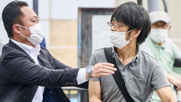 Tetsuya Yamagami, centre, holding a weapon, is detained near the site of gunshots in Nara, western Japan Friday, July 8, 2022. 