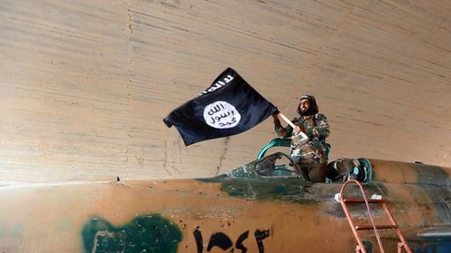 An Islamic State group fighter waves their flag from inside a captured government fighter jet following the battle for the Tabqa air base, in Raqqa, Syria. (AP Photo/ Raqqa Media Center of the Islamic State group)