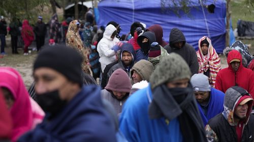 FILE - Migrants from Venezuela line up in the cold weather for hot drinks and food from volunteers at a makeshift camp on the U.S.-Mexico Border in Matamoros, Mexico, Friday, Dec. 23, 2022. In a ruling Tuesday, Dec. 27, the U.S. Supreme Court has decided to keep pandemic-era limits on immigration in place indefinitely, dashing hopes of immigration advocates who had been anticipating their end this week. (AP Photo/Fernando Llano, File)
