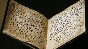 A university assistant shows fragments of an old Quran at the University in Birmingham. (AAP)