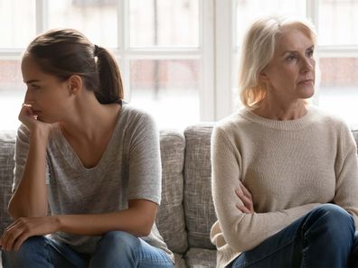 Daughter-in-law and mother-in-law sitting on a couch facing opposite ways