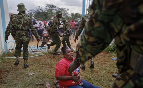 A woman who fell begs for mercy during clashes between rock-throwing supporters of President Uhuru Kenyatta and police at his inauguration ceremony after they tried to storm through gates to get in and were tear-gassed, at Kasarani stadium in Nairobi, Kenya  (AP Photo/Ben Curtis)