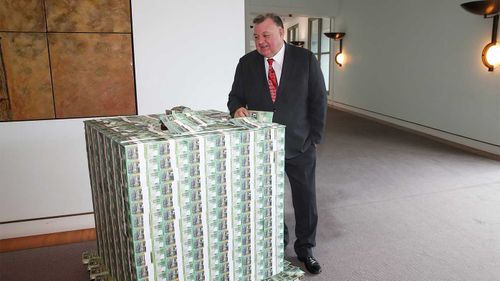 Independent MP Craig Kelly in front of a pallet of fake money.