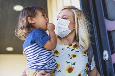 Mum wearing mask holding baby.