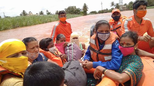 People stranded in flood waters watch others being rescued at Kolhapur in western Maharashtra state, India.