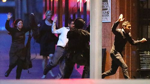 People flee from the Lindt Cafe, Martin Place during a hostage standoff on December 16, 2014 in Sydney, Australia. Police stormed the Sydney cafe  where lone gunman, Man Haron Monis, had been holding ten customers and eight employees. Hostage Tori Johnson was killed by Monis and hostage Katrina Dawson was killed by a police bullet ricochet during the raid. Monis was killed by police. 