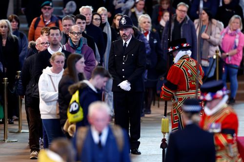 A police officer stands guard where Queen Elizabeth II's flag-draped coffin is lying in state on the catafalque at Westminster Hall.