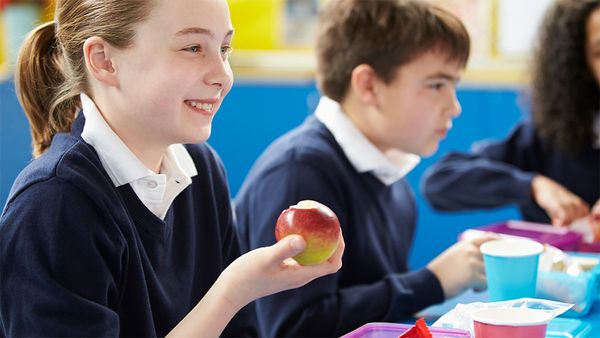 School kids eating lunch, student holding apple