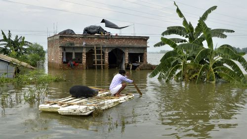 An Indian villager uses a banana raft outside his partially flooded house. (AFP)