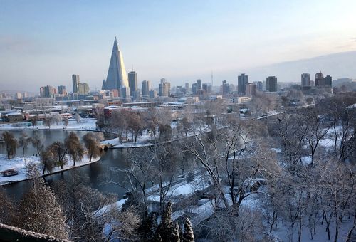 The pyramid-shaped Ryugyong Hotel towers over residential apartments and snow covered trees and fields.