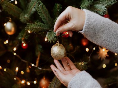 Woman decorating Christmas tree with baubles