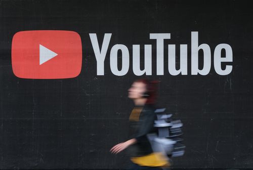 A young woman wearing headphones walks past a billboard advertisement for YouTube on September 27, 2019 in Berlin, Germany. YouTube has evolved as the world's largest platform for sharing video clips. (Photo by Sean Gallup/Getty Images)