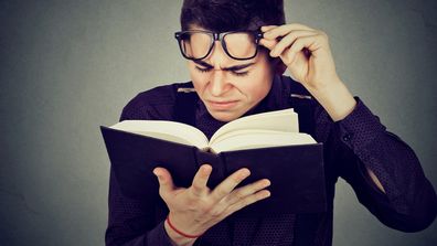 Man reading book confused reader poor vision glasses dictionary