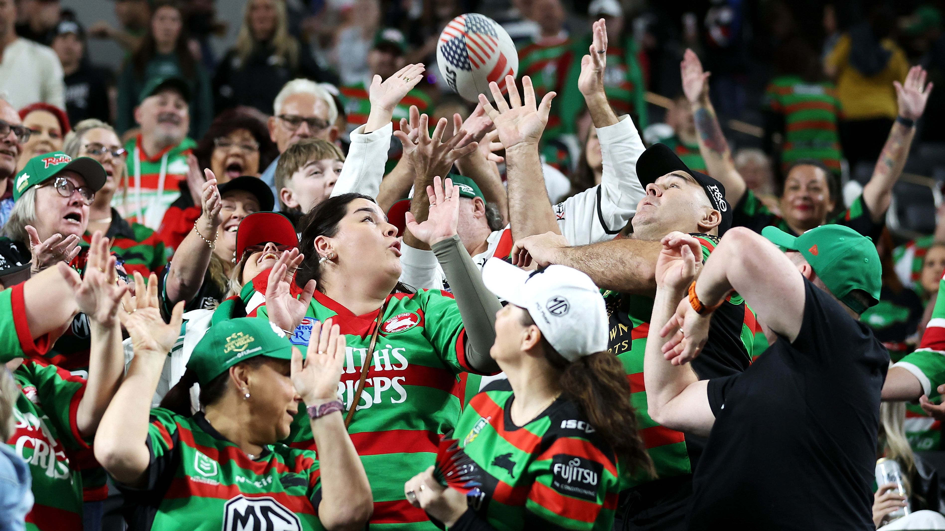 Supporters attempt to catch a football in the crowd before the round one NRL match between Manly Sea Eagles and South Sydney Rabbitohs at Allegiant Stadium.