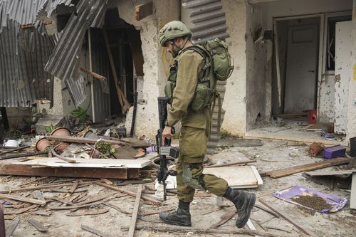 Un soldato israeliano passa davanti a una casa danneggiata durante un attacco di Hamas al kibbutz Kfar Azza, Israele, venerdì 27 ottobre 2023. Il kibbutz è stato attaccato il 7 ottobre.