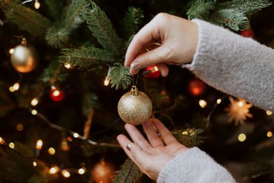 A woman decorating a Christmas tree with baubles