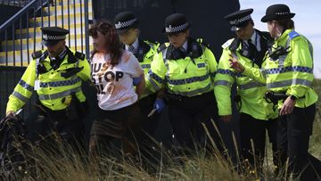 A Just Stop Oil protester is led away by police and security near the 17th hole during the second day of the British Open Golf Championships at the Royal Liverpool Golf Club in Hoylake, England, Friday, July 21, 2023 