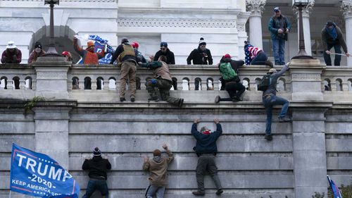 Supporters of President Donald Trump climb the West wall of the the US Capitol.