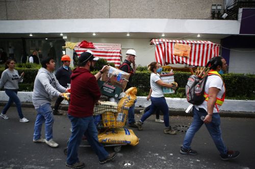 Volunteers offering their services at sites of earthquake damage mingle with people taking donations of pet food to a collection center, as they walk along Insurgentes Avenue in the Roma neighbourhood. (AP)