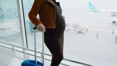 Pregnant woman at the airport with a suitcase