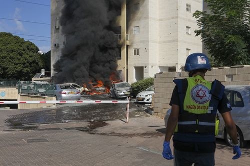 Cars are burning after a rocket fired from the Gaza Strip hit a parking lot and a residential building in Ashkelon, southern Israel, Saturday, Oct. 7, 2023.  