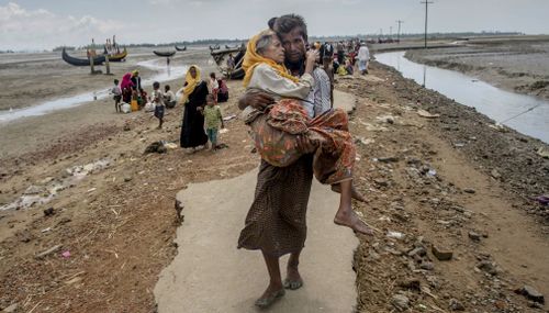 Rohingya Muslim man Abdul Kareem walks towards a refugee camp carrying his mother Alima Khatoon after crossing over from Myanmar into Bangladesh. (AP)