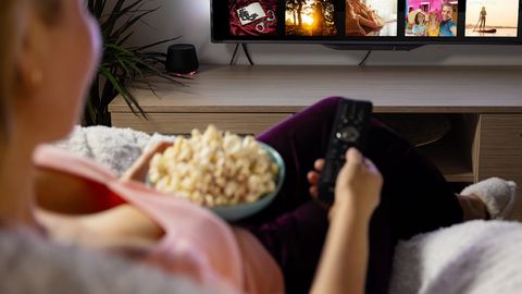 woman watching TV eating popcorn