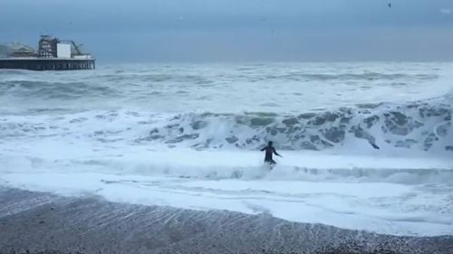 The woman was engulfed by a wave as her dog disappeared behind it, desperately tried to stay afloat. (Youtube / Juice Brighton)