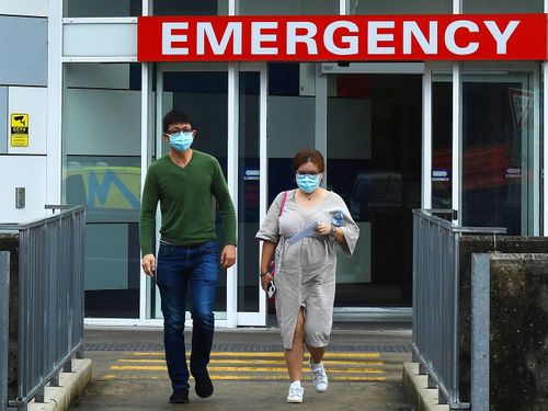 Two people wearing face masks walk out of the emergency entrance at Westmead Hospital, in Sydney's west.