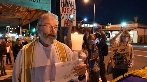 Father Denis Scanlan (left) and protestors are seen outside the Kangaroo Point Central Hotel in Brisbane, Friday, June 12, 2020