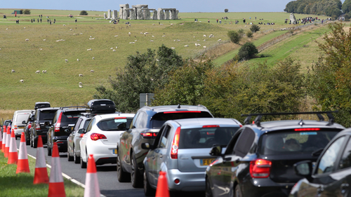 Traffic builds up on the main road near Stonehenge, seen in background, as people try to get away for the holiday weekend, Friday Aug. 28, 2020. (Andrew Matthews/PA via AP)