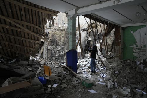 A woman takes photos of a destroyed accommodation building near a checkpoint in Brovary, outside Kyiv, Ukraine, Tuesday, March 1, 2022.