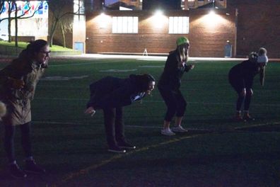 Women gather in high school yard to scream together. 