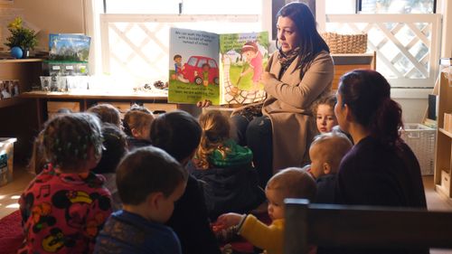 A teacher at a Sydney child care centre reads to young children.