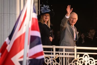 King Charles III waves from the balcony as he visits Luton Town Hall on December 6, 2022 in Luton, England 