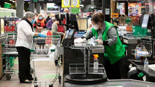 A staff member wipes down the checkout area at Woolworths in Marrickville Metro, where a man who has since tested positive to COVID-19 visited.