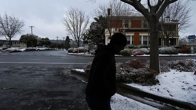 Une personne marche le long de la rue principale où la neige est tombée à Oberon. 