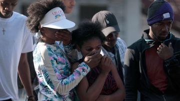 Bystanders look at the bodies of alleged gang members that were set on fire by a mob after they were stopped by police while traveling in a vehicle in the Canape Vert area of Port-au-Prince, Haiti.